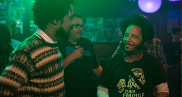 Boots Riley and LaKeith Stanfield smiling at each other on the set of the "Sorry To Bother You" film.