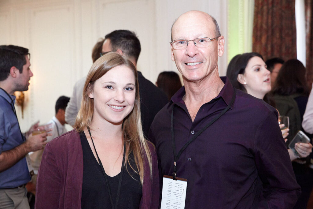 A young woman and older man smiling together during a conference networking session.