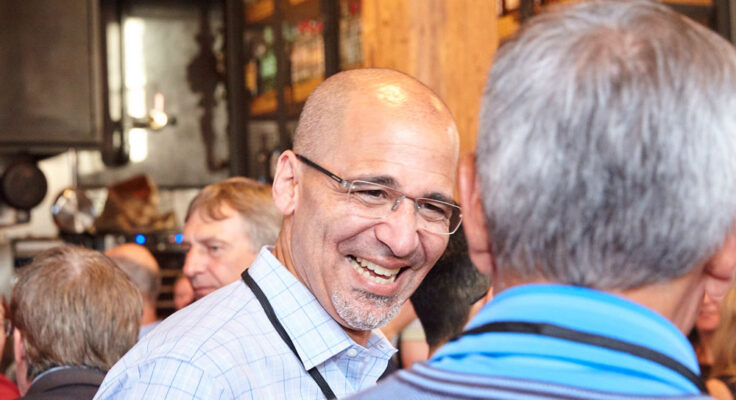 William Rogers smiling and talking to someone during an event reception.