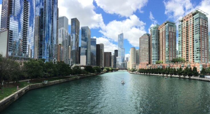 The Chicago river shown flowing in between high rise buildings on either side of it.