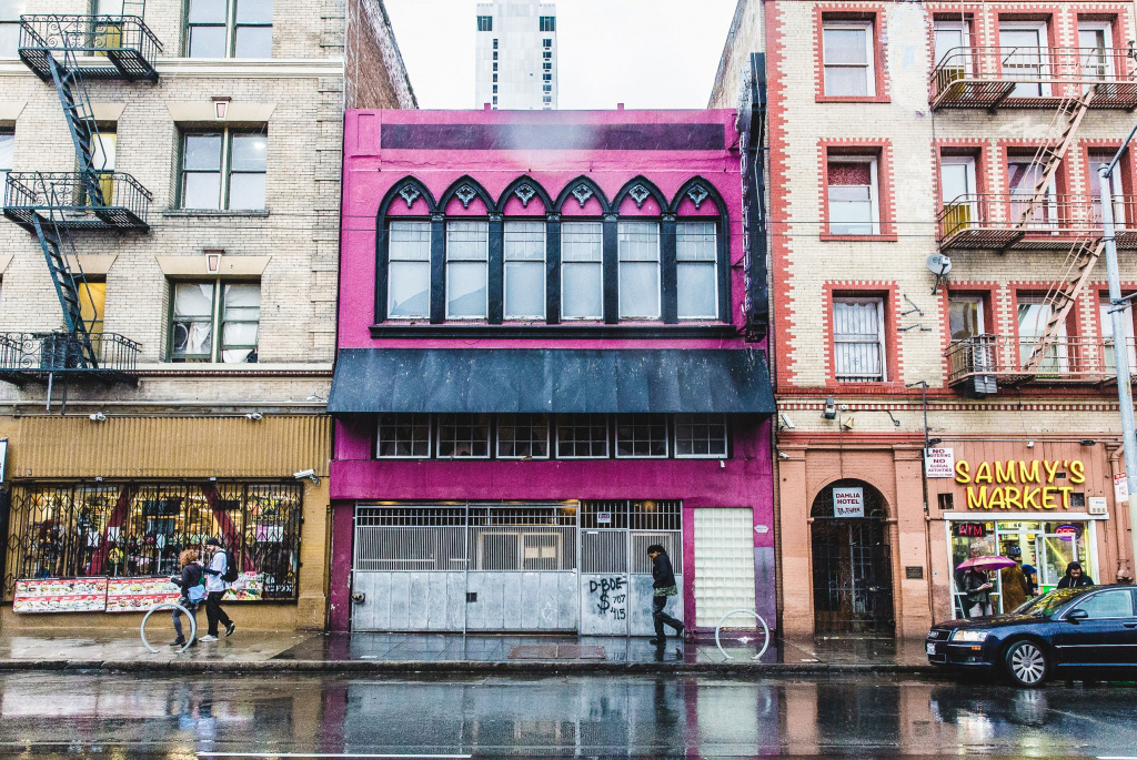 A bright pink building sandwiched between two larger ones.