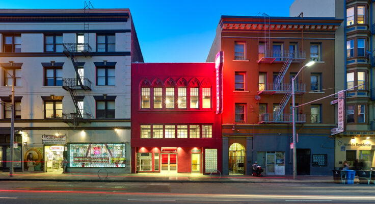 CounterPulse's three-story magenta building with light-filled windows is sandwiched between two gray buildings in San Francisco.
