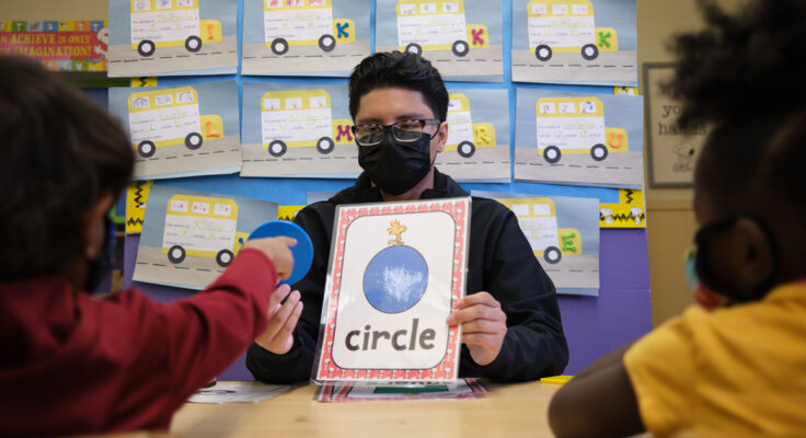 Tutor holding a flash card with a shape and the word circle on it.|Tutor holds a whiteboard with an "R" written on it