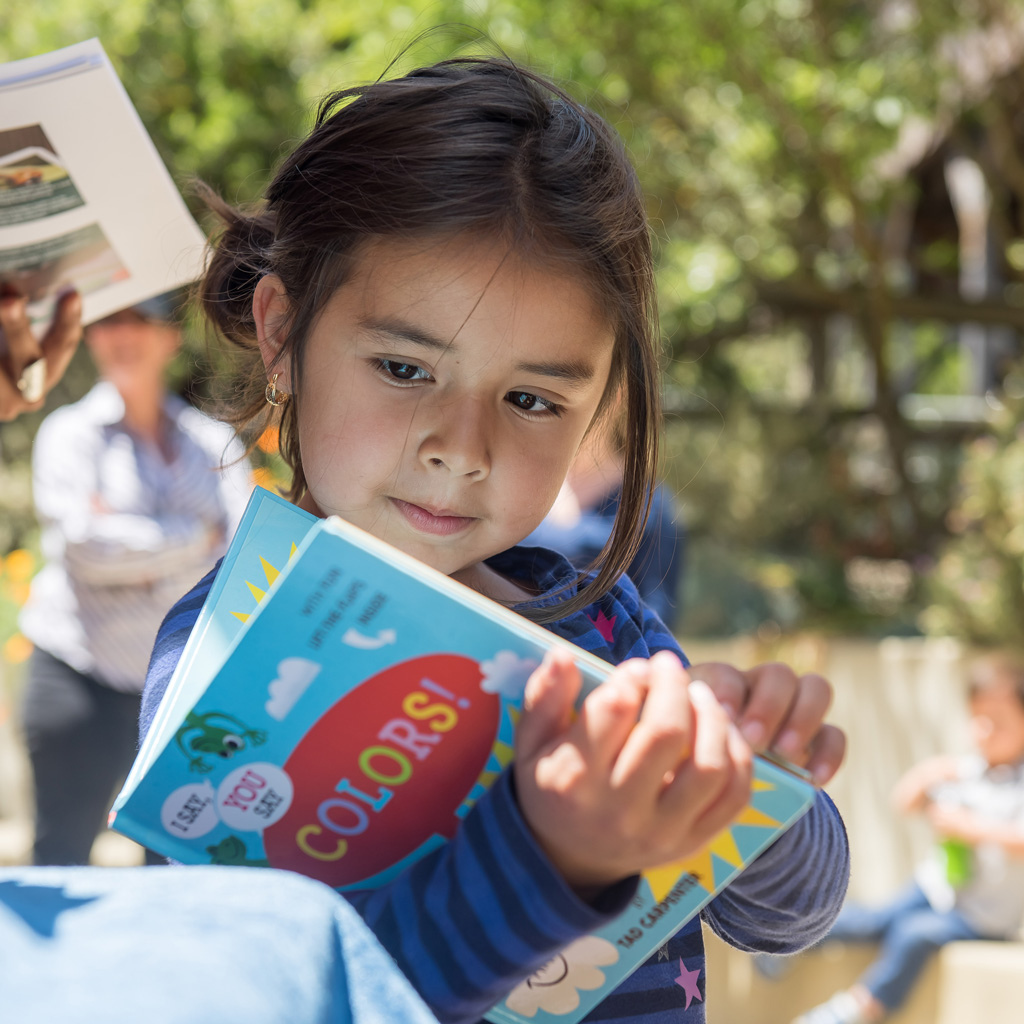 A young child opening a book about colors.