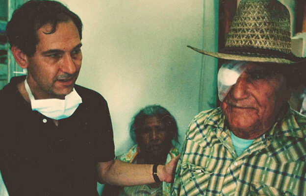Kenneth Rainin with his hand on the shoulder of a man with one eye covered with white gauze and tape.