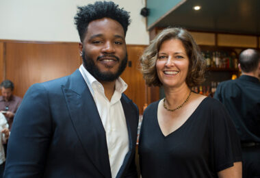 Ryan Coogler and Jen Rainin standing close to each other while smiling for the camera.