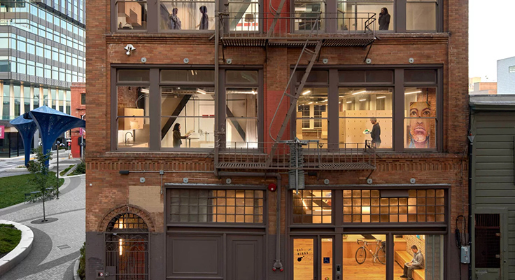 A multistory building in San Francisco with windows lit from within showcasing people moving about.