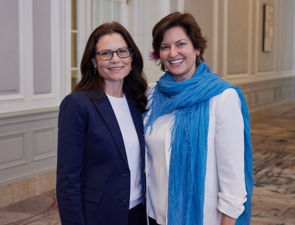 Two women standing shoulder to shoulder smiling