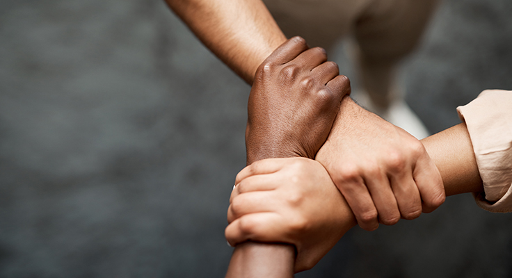 Three arms interlocked to form a triangle, demonstrating uniting in strength and solidarity.