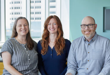 Carissa Ibert, Liz O’Malley and Patrick Taylor seated together, smiling at the camera.