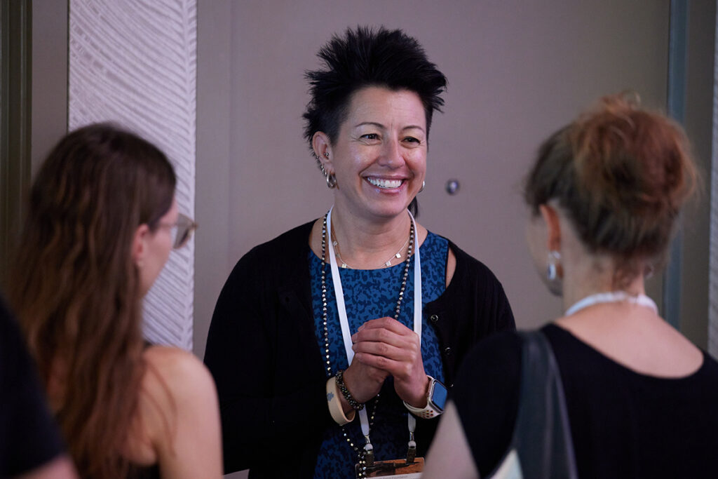 Dr. Laura Wilson smiling at two Symposium attendees.