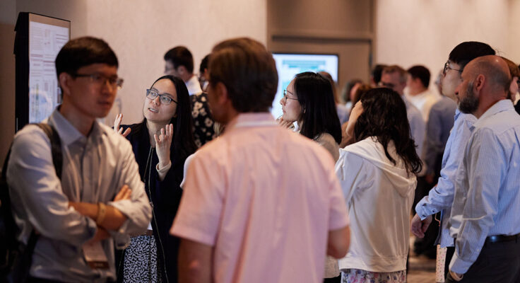 Many people connecting and exploring research during a poster session.