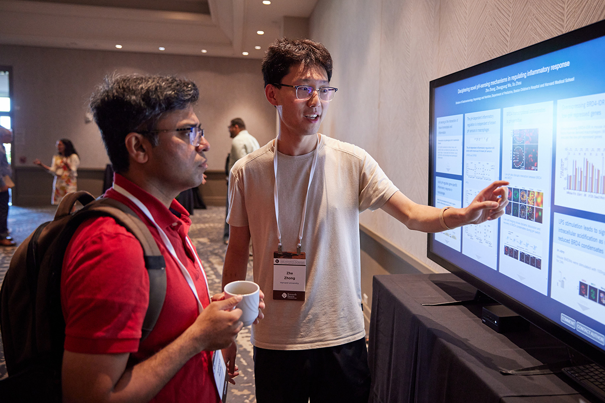 A person explaining their research, which is displayed on a TV screen.
