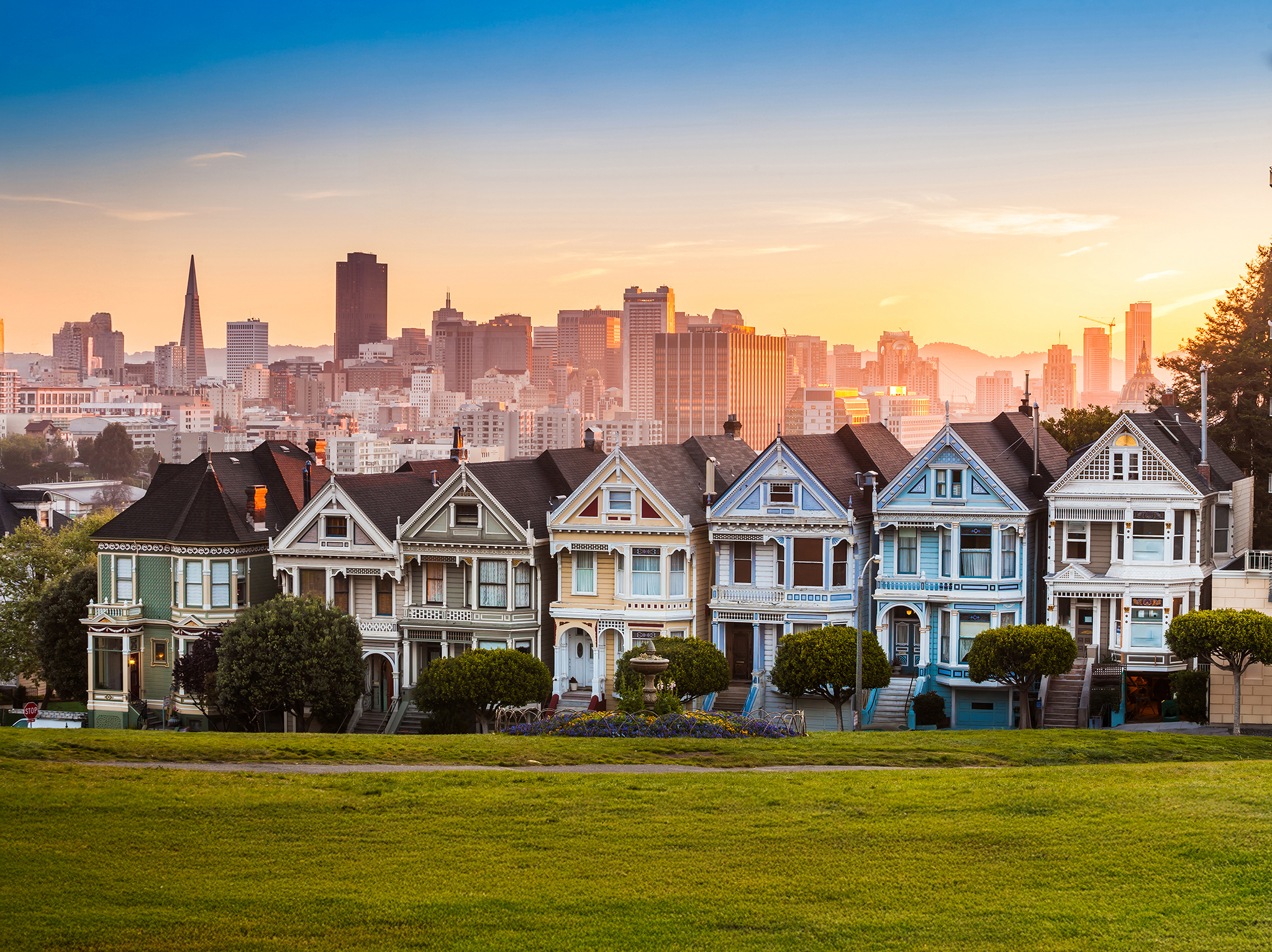 The colorful Victorian houses known as the Painted Ladies of San Francisco in Alamo Square pictured at sunset.