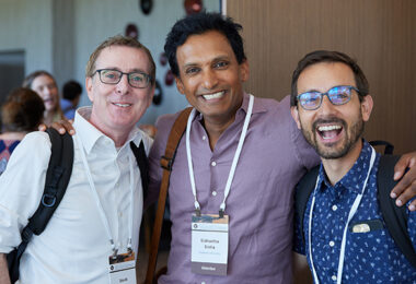 Three people with their arms around each other smiling broadly at the camera.