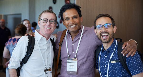 Three people with their arms around each other smiling broadly at the camera.