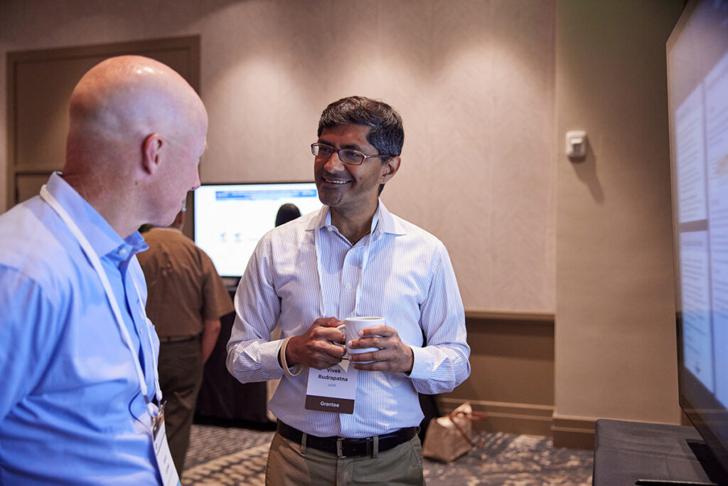 Two people talking in front of a digital research poster.