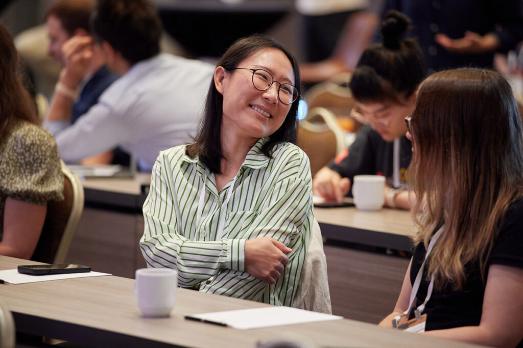Two people talking in the audience before a main stage presentation.