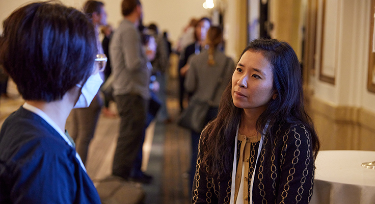 Dr. Julie Saiki speaking with another Symposium attendee while sharing her research in a digital poster session.