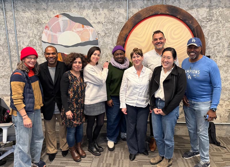 Nine people stand posing for the camera.
