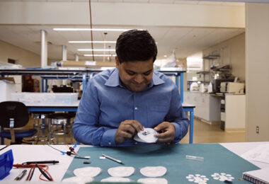 Dr. Anand Navalgund in a lab holding G-Tech Medical's novel wireless patch.