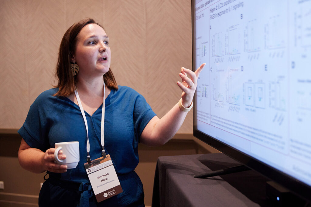 A scientist pointing at their research findings on a large screen.
