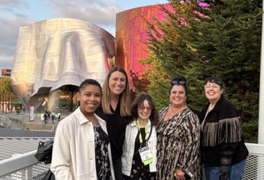 Five people standing in front of two buildings in Seattle with interesting architecture.