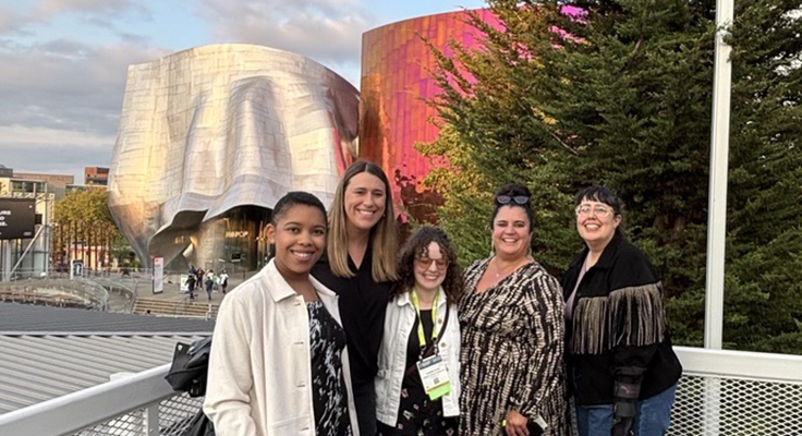 Five people standing in front of two buildings in Seattle with interesting architecture.