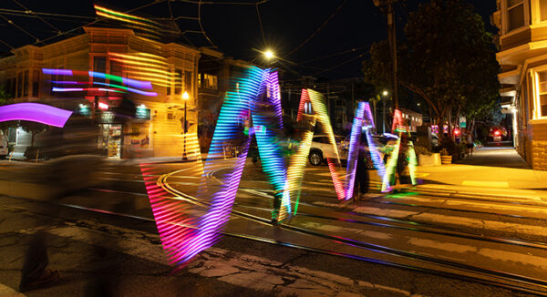 Trails of colorful light along a crosswalk.