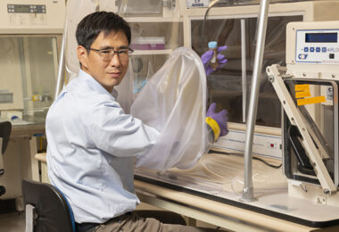 A researcher working in the lab, his gloved hands holding a sample.