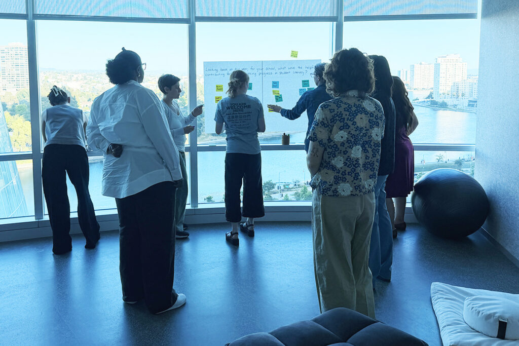 People collaborating in a room, putting post-it notes on a large white sheet of paper.
