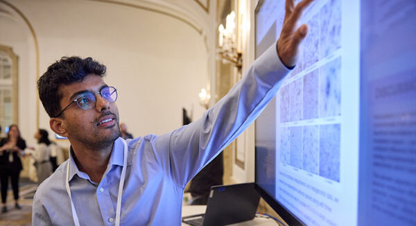 A person pointing at a large screen displaying a research poster.