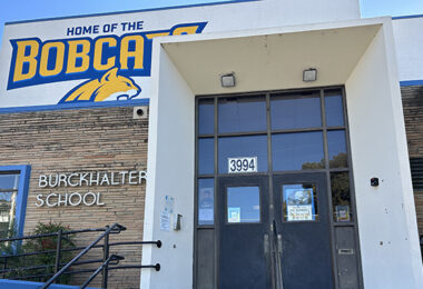 The entrance to Burckhalter Elementary School, which has a blue and yellow mural that reads, "Home of the Bobcats" with the head of a bobcat pictured mid-vocalization.