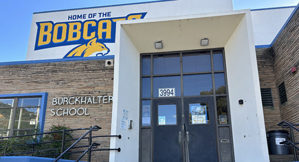 The entrance to Burckhalter Elementary School, which has a blue and yellow mural that reads, "Home of the Bobcats" with the head of a bobcat pictured mid-vocalization.