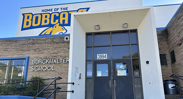 The entrance to Burckhalter Elementary School, which has a blue and yellow mural that reads, "Home of the Bobcats" with the head of a bobcat pictured mid-vocalization.