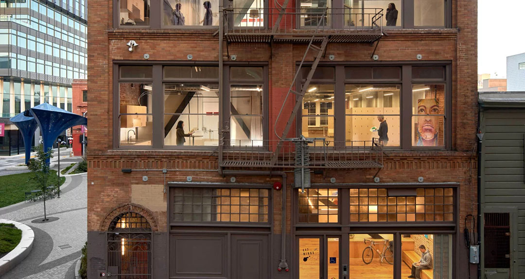A multistory building in San Francisco with windows lit from within showcasing people moving about.